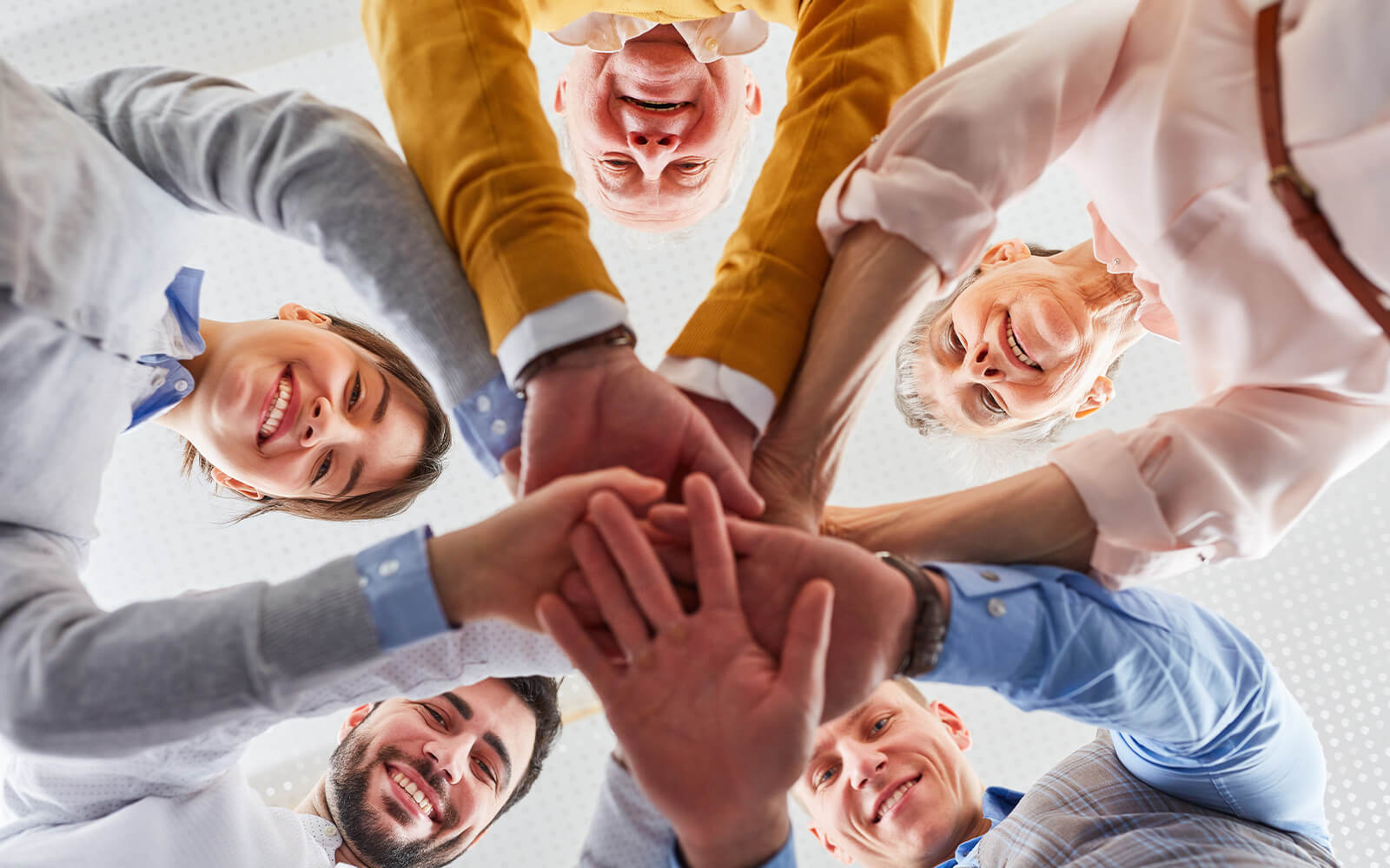 Menschen, die im Kreis stehen und ihre Hand ausgestreckt übereinander gelegt haben