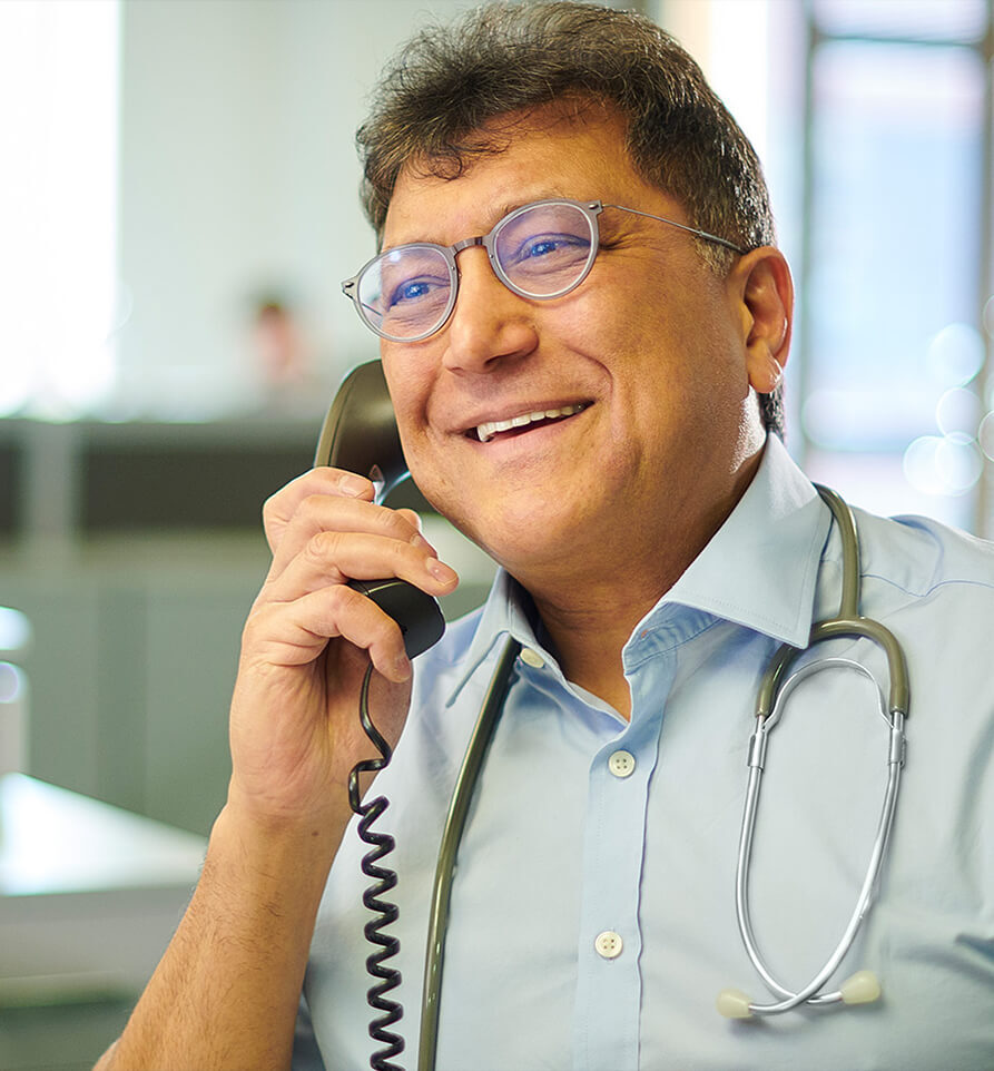 Arzt mit Stethoskop telefoniert im Büro – Symbolbild für die Telefon-Sprechstunde mit dem Betriebsarzt zur schnellen Unterstützung